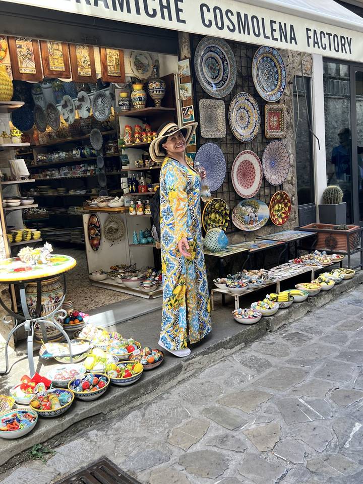 Personne devant un magasin de céramique avec des assiettes colorées et de l'artisanat.