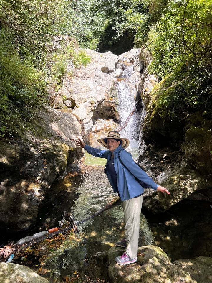 Personne debout près d'une cascade avec une végétation luxuriante.