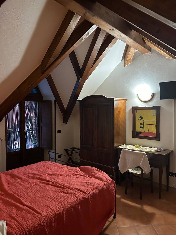 Intérieur d'une chambre avec poutres en bois et couvre-lit rouge.