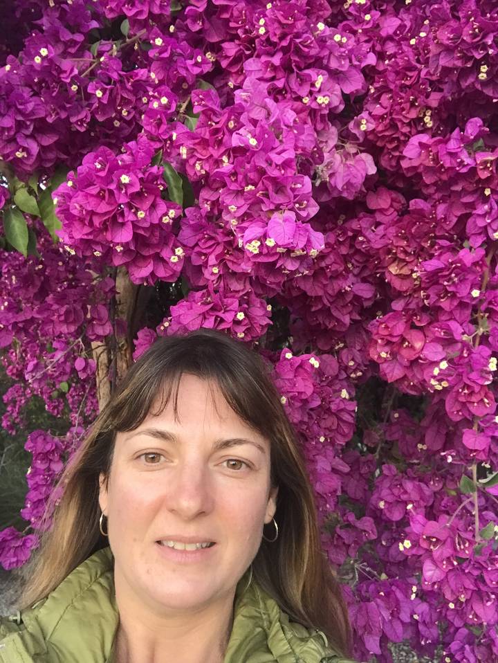 Femme allongée à côté de fleurs violettes éclatantes.
