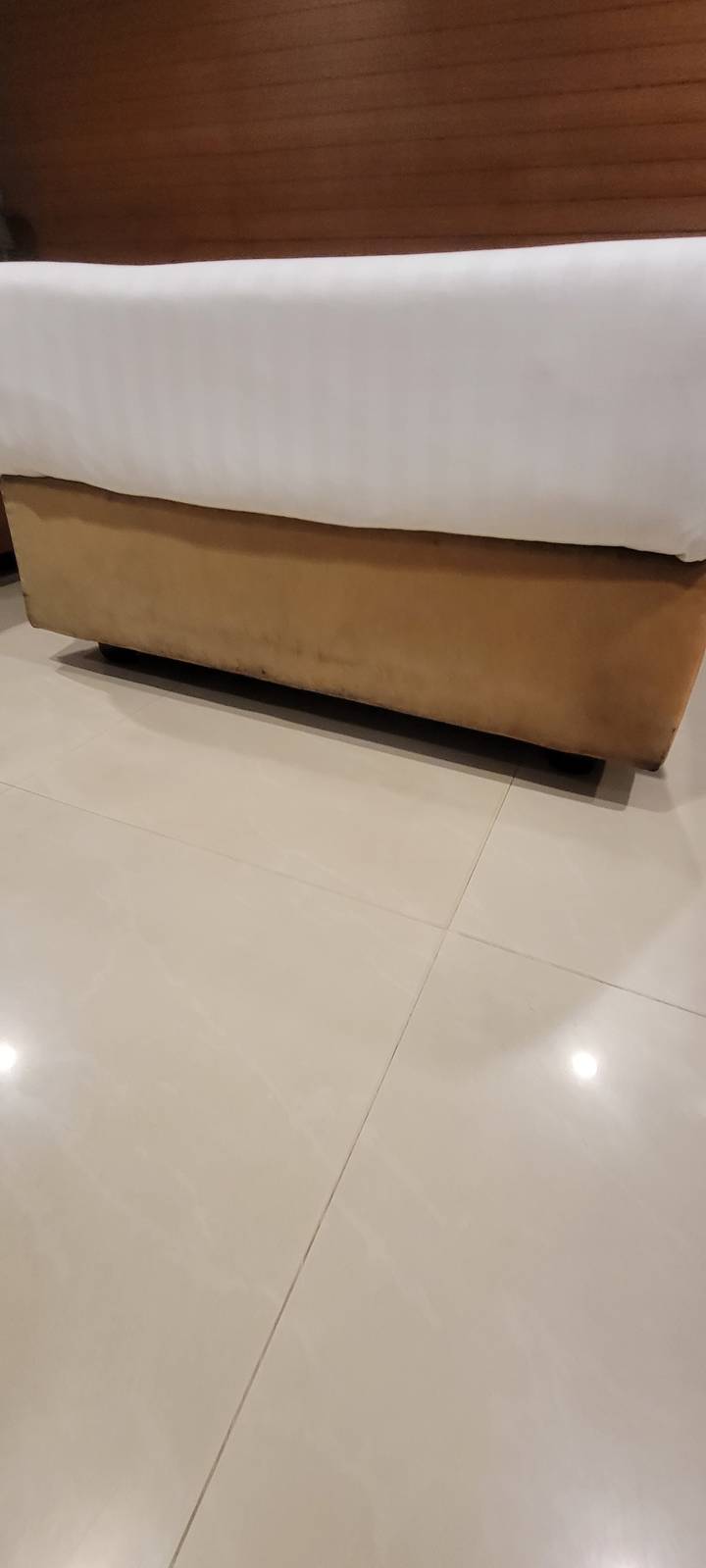 Gros plan d'un coin de lit et d'un sol carrelé.