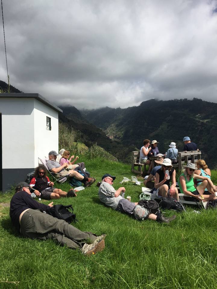 Des gens se reposent sur une zone herbeuse avec des montagnes en arrière-plan.