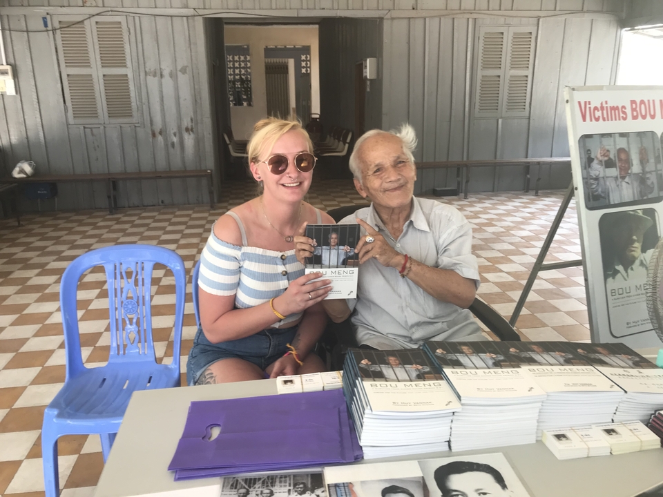 Femme souriante avec un homme âgé lors d'une séance de dédicace.