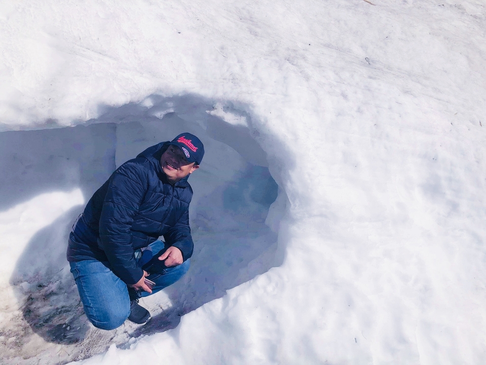 Personne accroupie dans une grotte de neige.