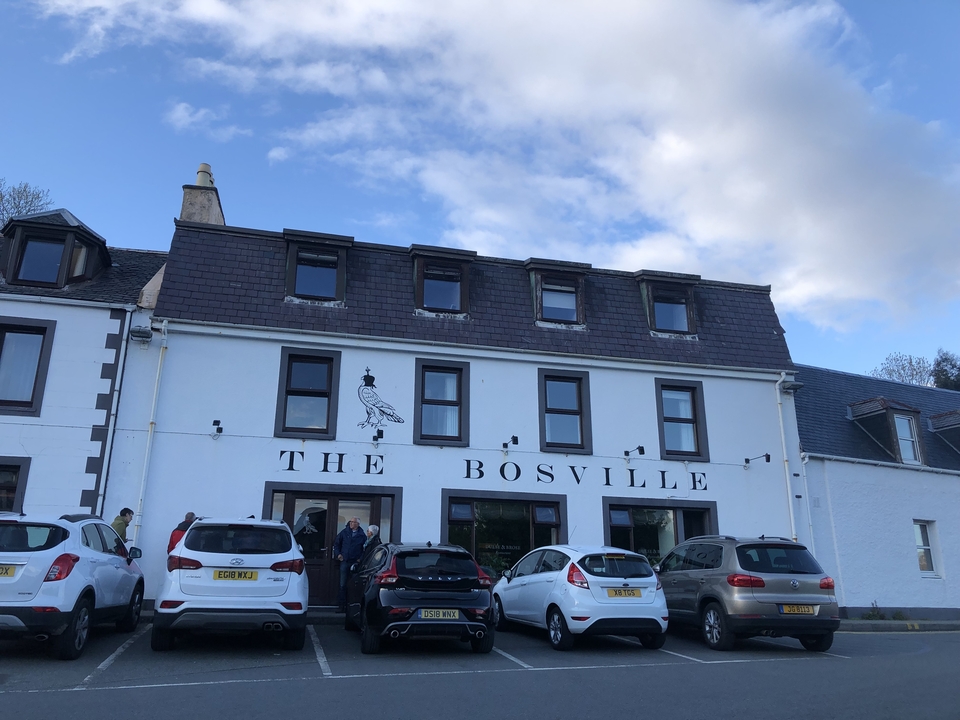 A group of cars parked in front of a white building with the sign 'The Bosville.'