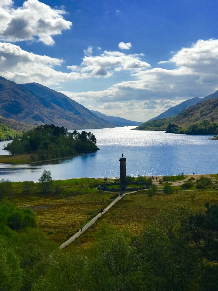 Un paysage magnifique d'un lac entouré de montagnes sous un ciel bleu.