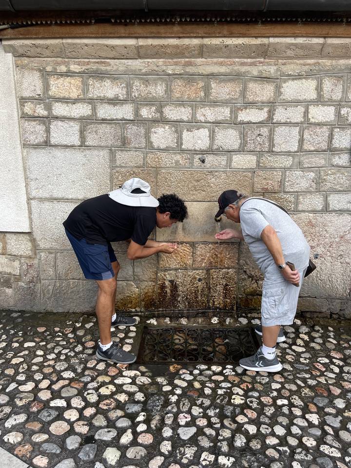 Deux personnes buvant à une fontaine publique.