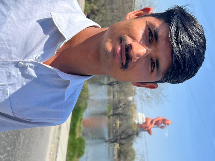 Gros plan d'un homme qui pose avec une grande statue en arrière-plan.