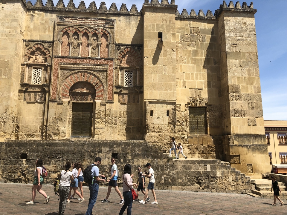 Mur de bâtiment historique avec sculptures complexes, des gens marchent à proximité.