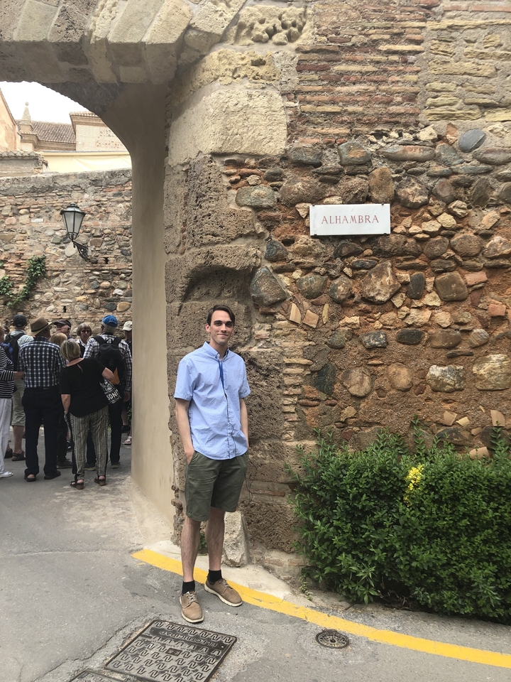 Personne posant devant l'Alhambra avec un mur de pierre en arrière-plan.