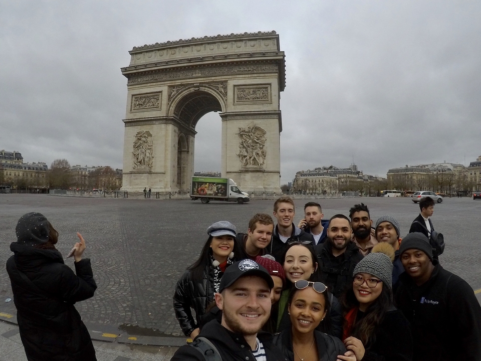 Group of people taking a selfie in front of the Arc de Triomphe.