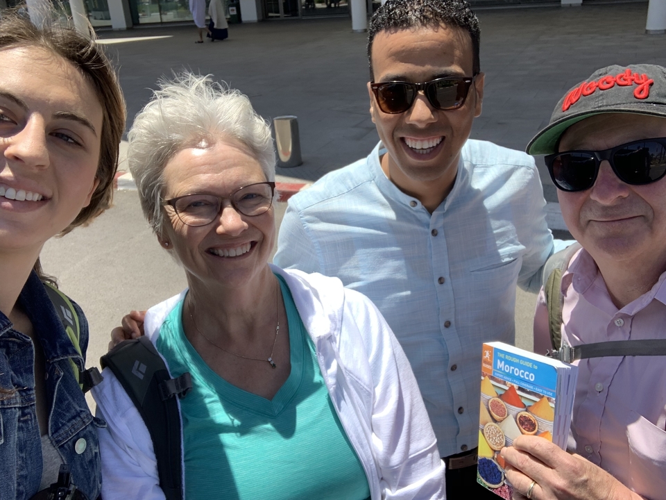 Groupe de personnes souriantes avec un guide de voyage du Maroc.