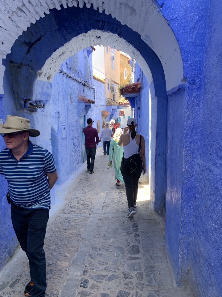 Des gens qui marchent dans une ruelle peinte en bleu.