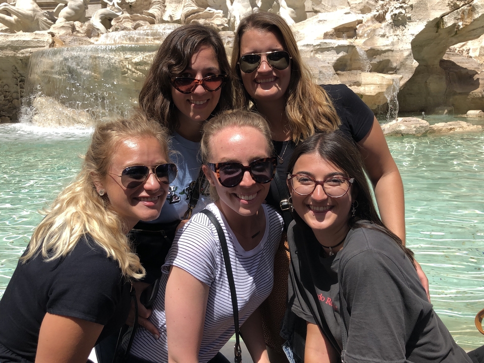 Groupe d'amis posant devant une fontaine.