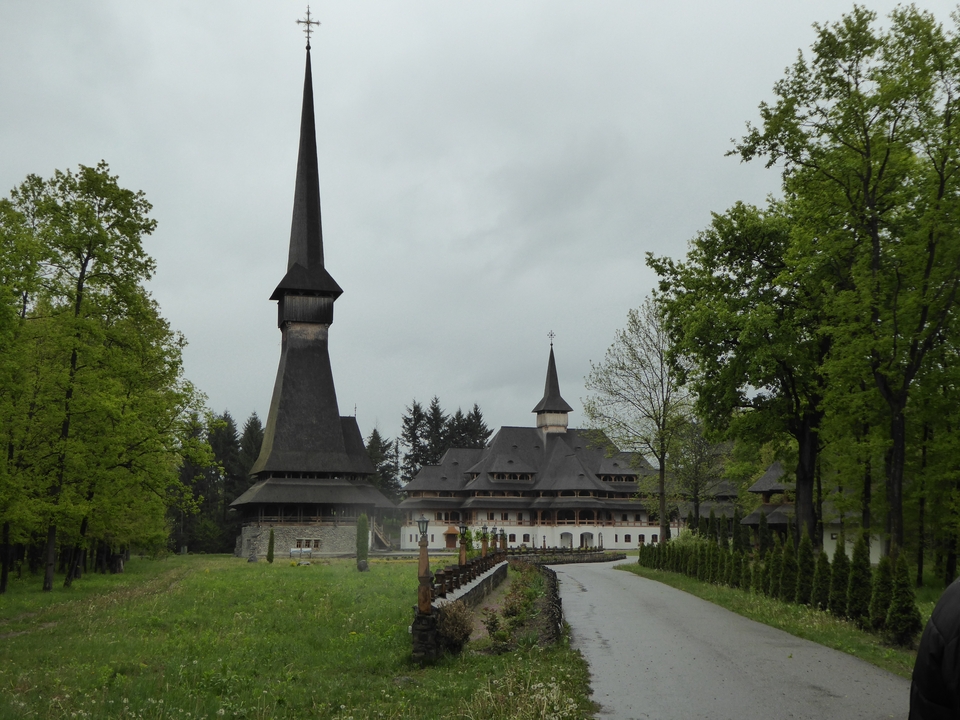 Monastère en bois avec de hautes flèches entouré d'arbres.