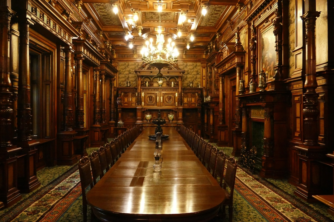 Salle à manger de palais luxueux avec boiseries ornées et lustres.