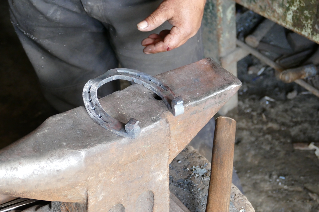 Gros plan d'un marteau et d'une enclume avec un fer à cheval.