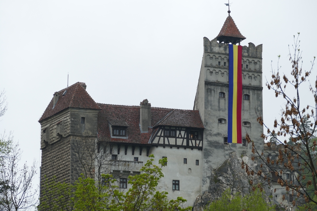 Château avec des arbres environnants et un grand drapeau suspendu.