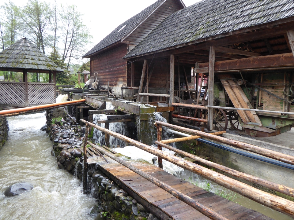 Moulin à eau rustique au bord d'un ruisseau avec des structures en bois.