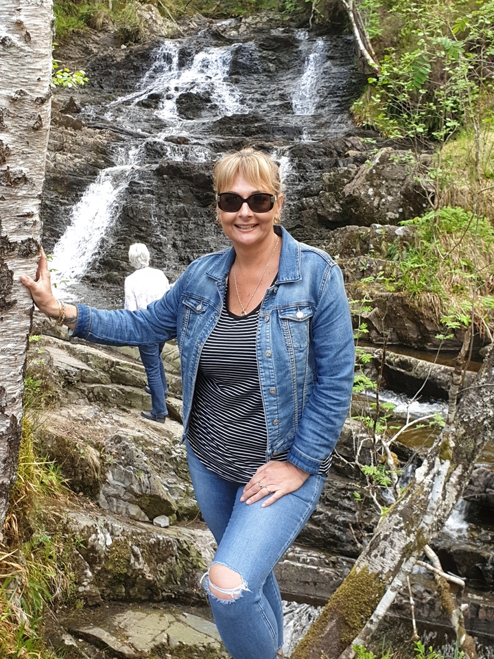 Woman poses in front of a waterfall.