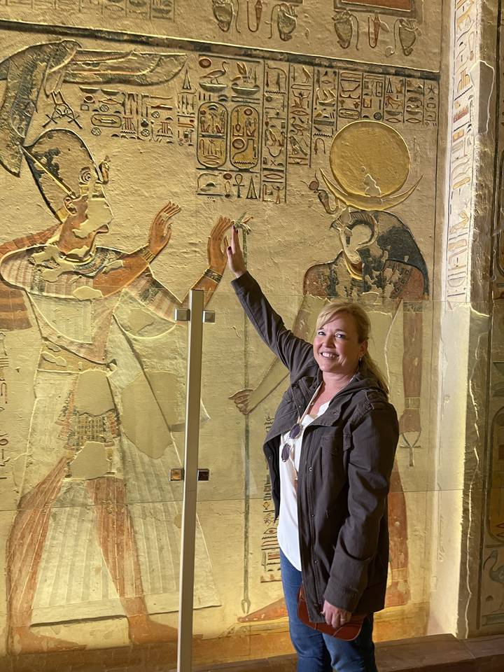 Personne pointant du doigt un mur avec de l'art égyptien antique.