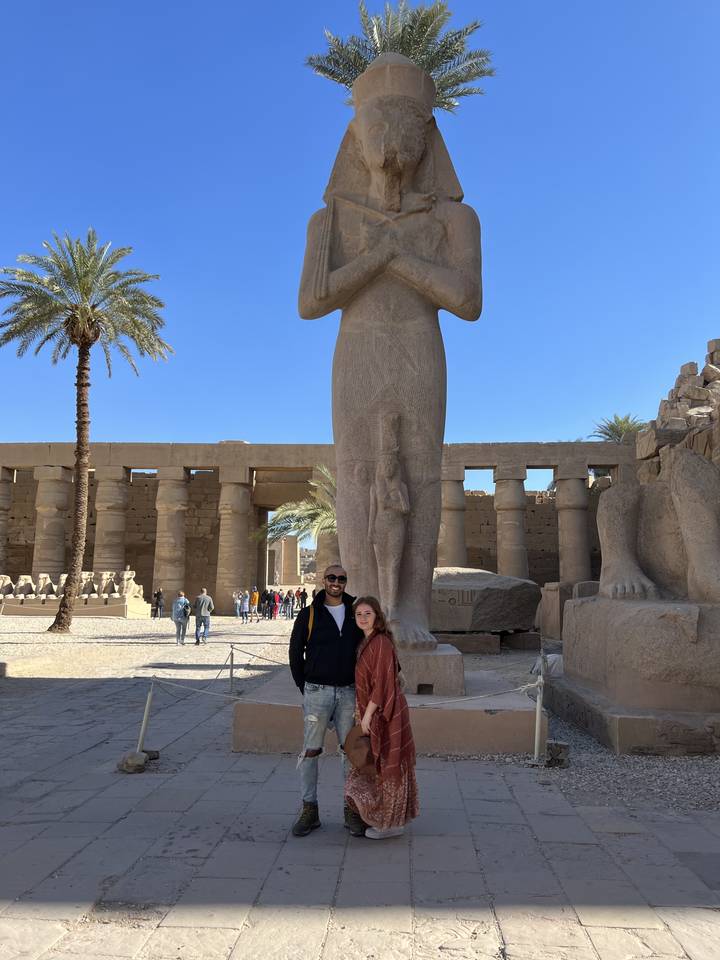 Deux personnes debout devant une statue égyptienne dans un complexe de temples.