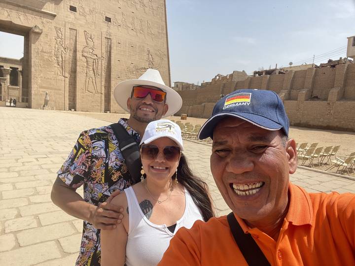 Trois amis souriants avec un site historique en arrière-plan.