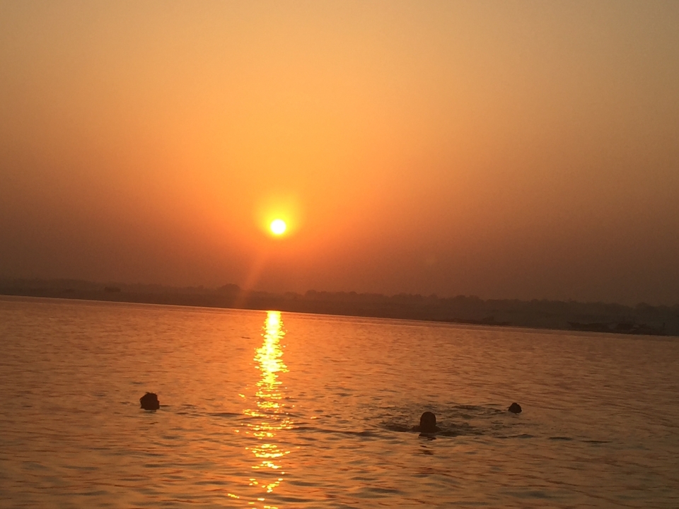 Un lever de soleil pittoresque au-dessus d'une rivière avec des gens qui nagent.