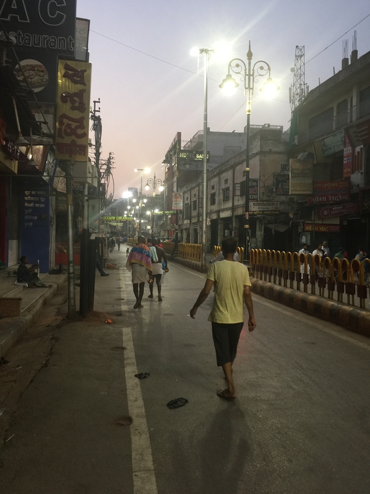 Une rue animée avec des gens et diverses enseignes de magasins au crépuscule.