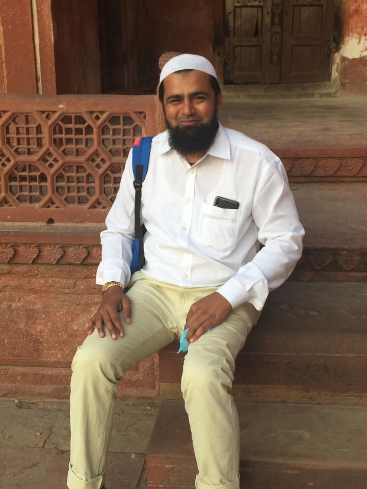 Personne assise sur des marches en pierre portant une chemise blanche.