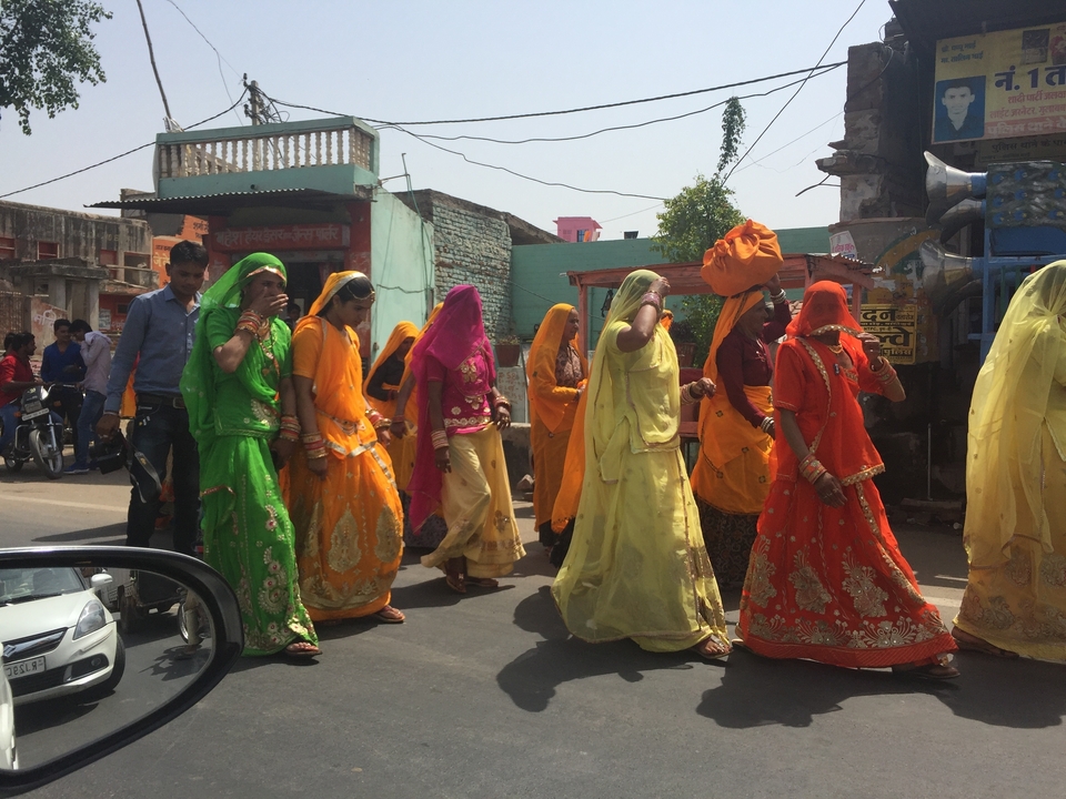Des gens en tenues traditionnelles colorées marchant dans la rue.