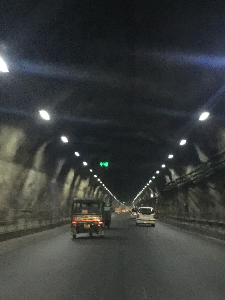 Tunnel faiblement éclairé avec des voitures qui le traversent.