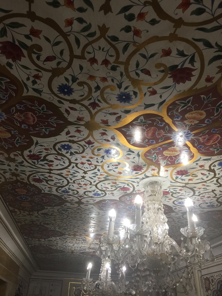 Plafond orné avec des motifs floraux et un lustre.