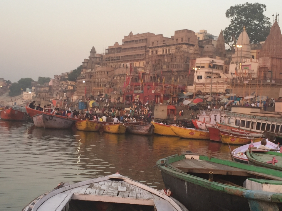 Un front de rivière avec des bateaux colorés et une foule animée à Varanasi.