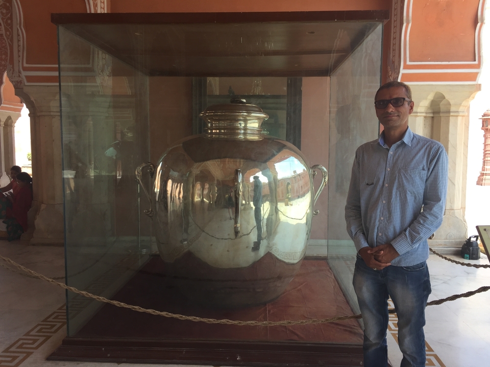 Homme posant à côté d'une grande exposition argentée.