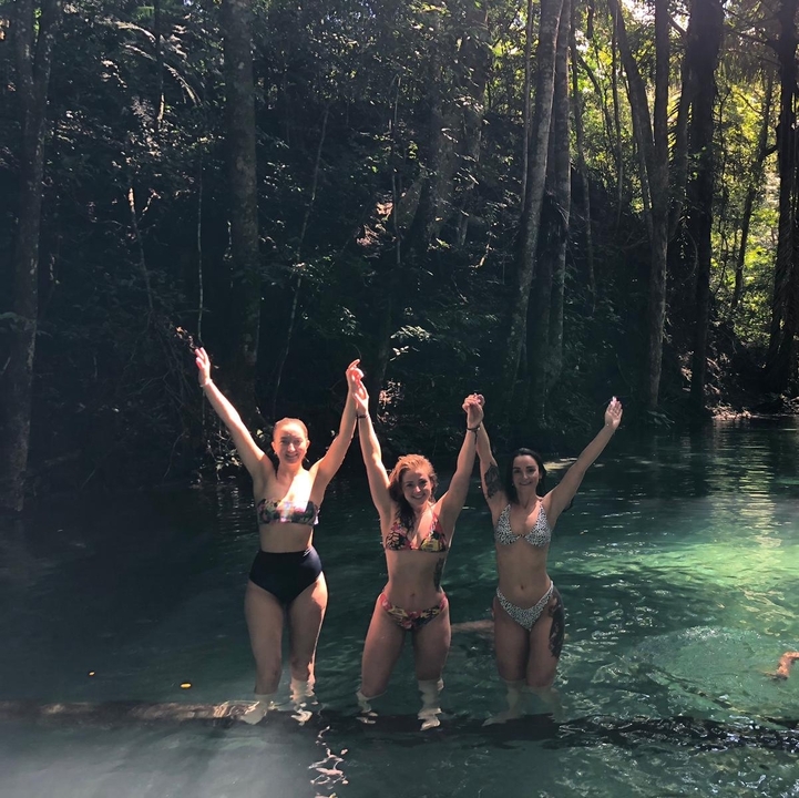 Three women enjoying a swim in a natural setting.