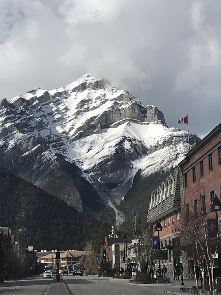 Sommet de montagne enneigé avec un drapeau canadien visible.