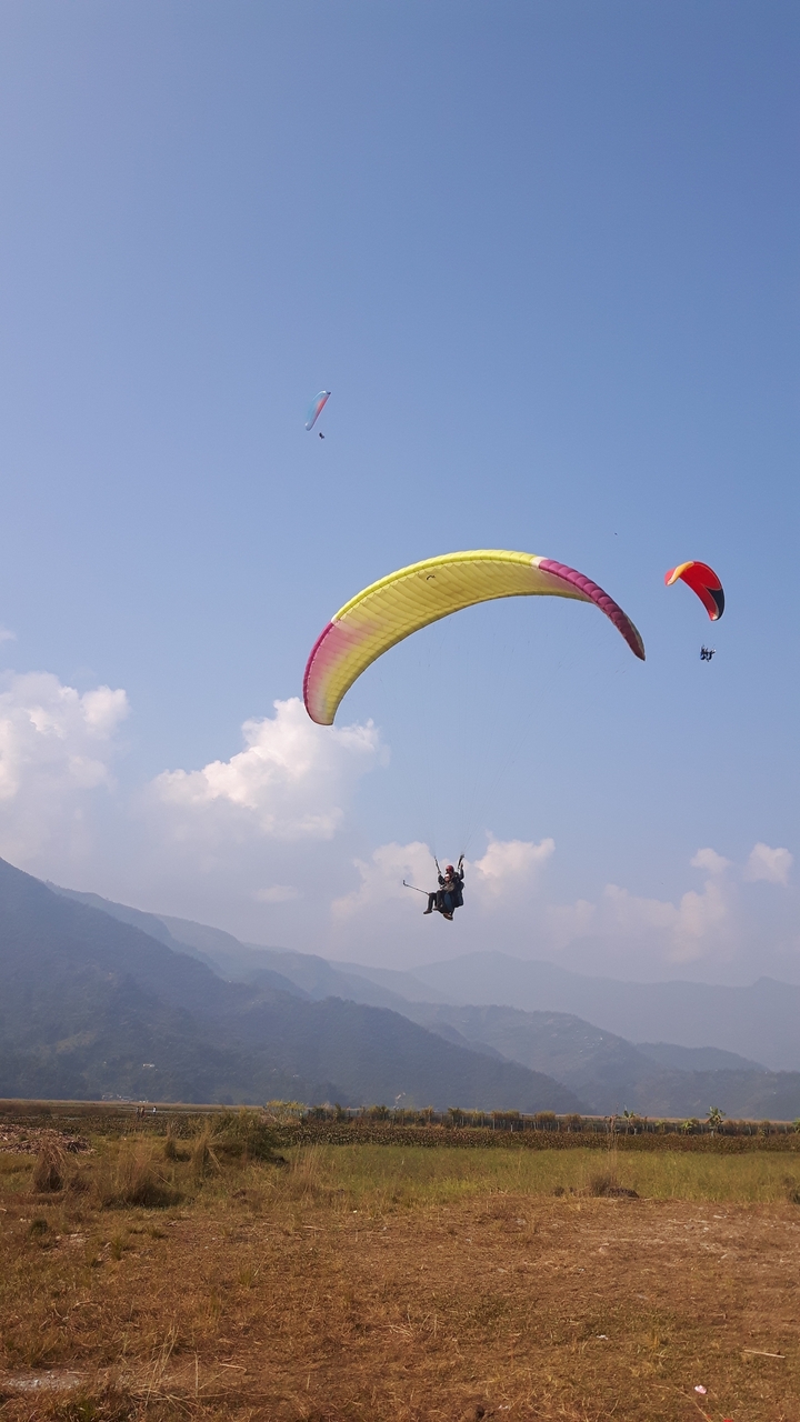 Des parapentistes dans le ciel avec des montagnes en arrière-plan.