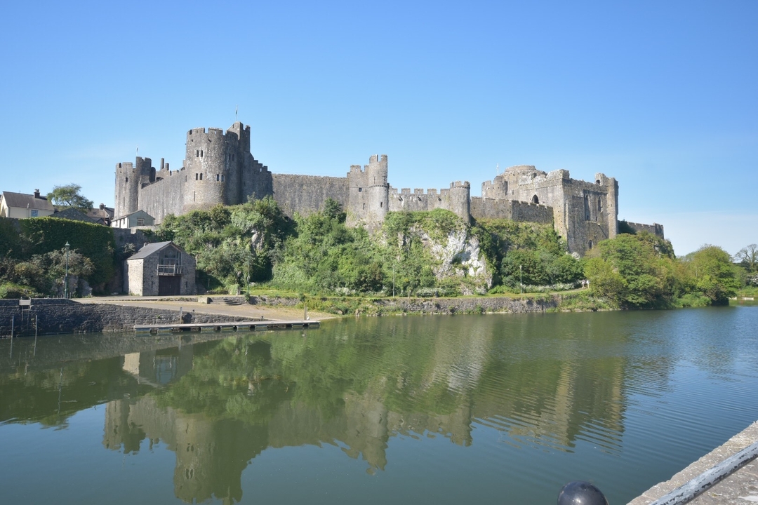 Château de Pembroke avec son reflet sur l'eau calme.