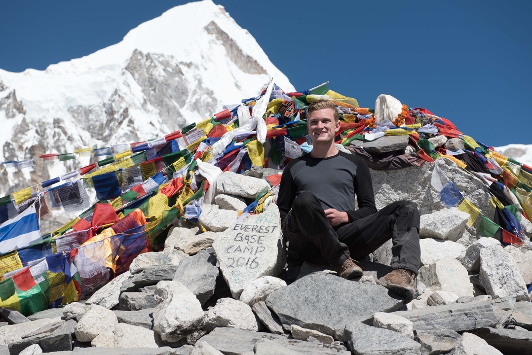 Une personne assise sur des rochers au camp de base de l'Everest avec un panneau.