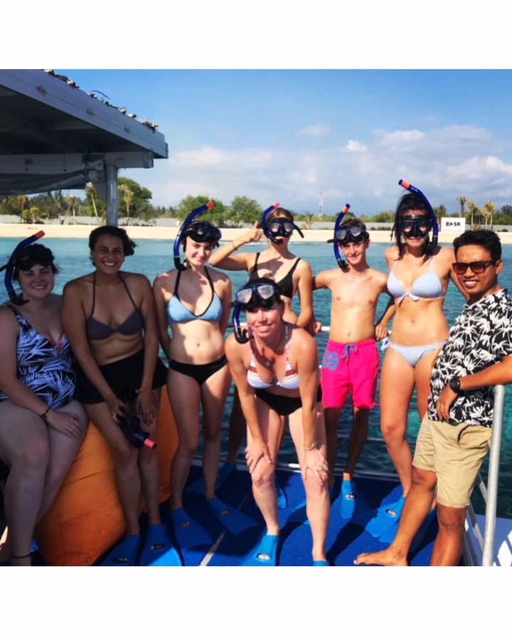 Groupe de personnes posant avec un équipement de plongée en apnée près de l'eau.
