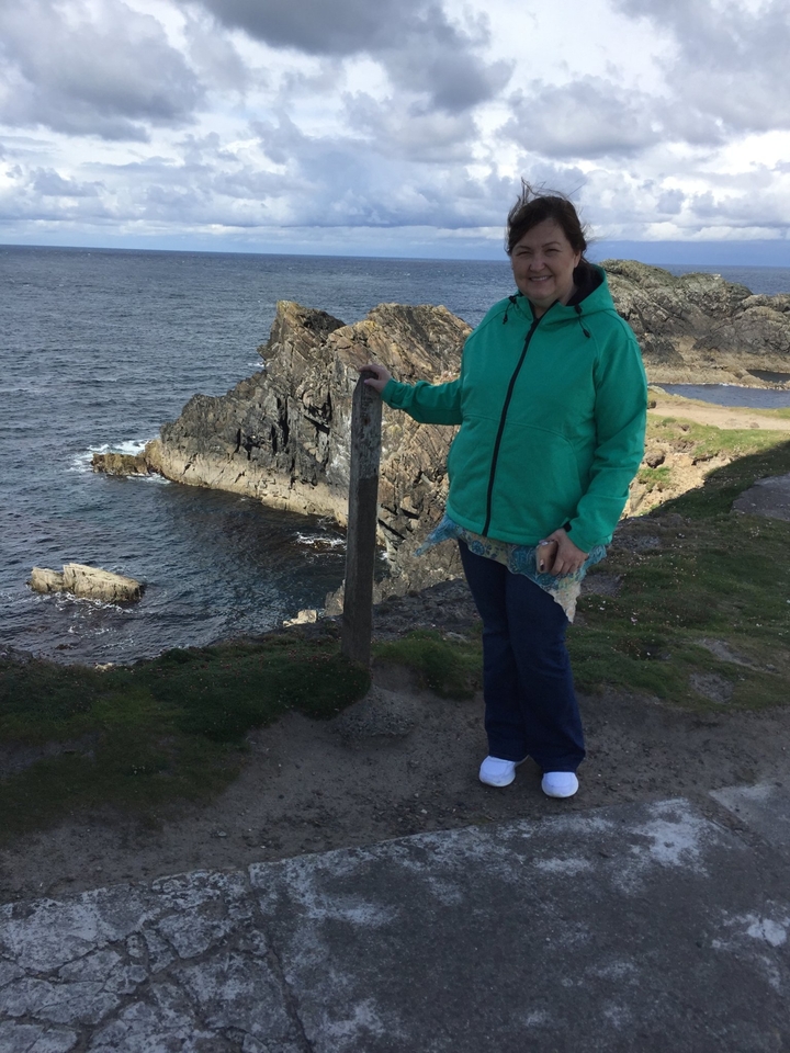 Personne debout sur une falaise avec la mer en arrière-plan.