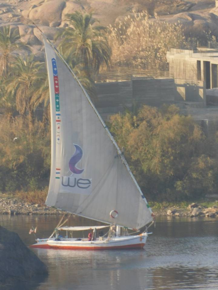 A sailboat on a river surrounded by nature.