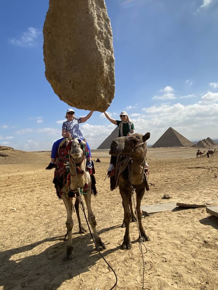 Tourists on camels in a desert landscape near pyramids