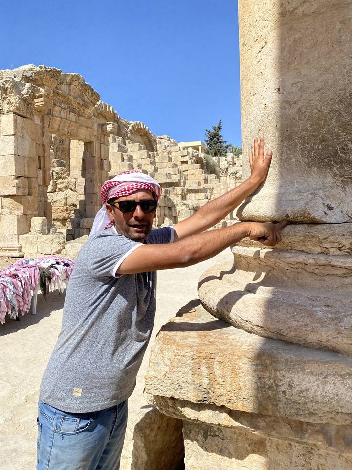 Man posing with an ancient stone column.