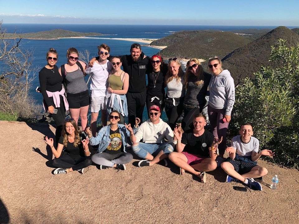 A group of people posing with a scenic ocean view in the background.