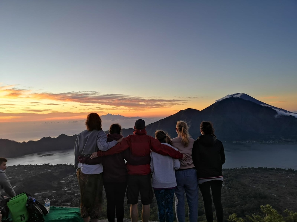 A group of people overlooking a scenic mountain sunrise.