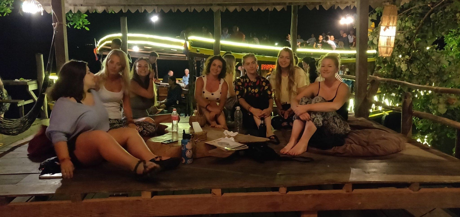 Un groupe de personnes assises ensemble dans un cadre extérieur nocturne avec des lumières.