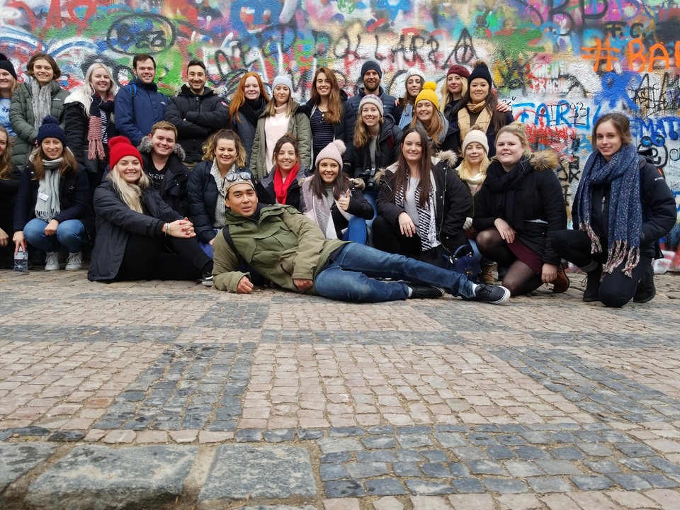 Un grand groupe de personnes posant devant un mur couvert de graffitis.