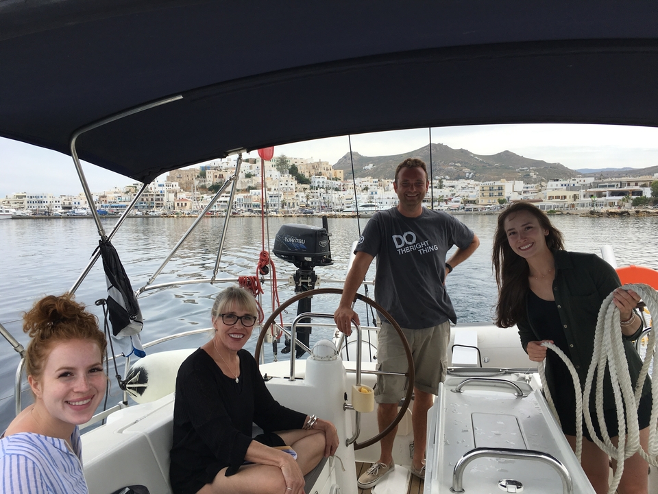 Groupe profitant d'une sortie en voilier, avec une ville pittoresque en arrière-plan.